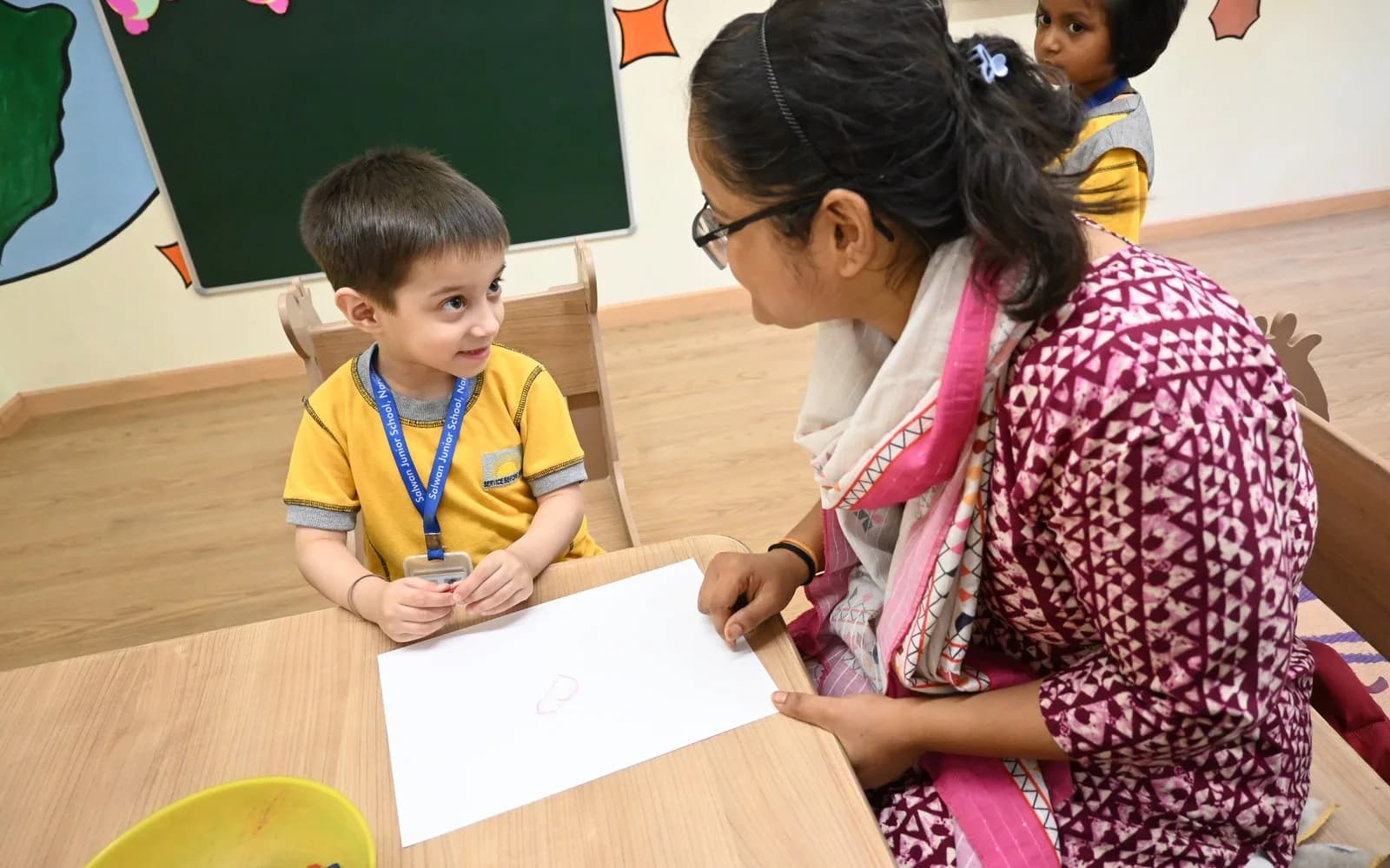 A teacher speaking individually with a young Montessori learner